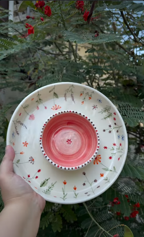 Hand holding a chip and dip platter with a pink centre bowl and red wildflower details